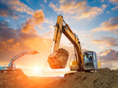 excavator in construction site on sunset sky background