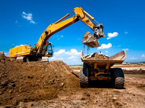 Industrial truck loader excavator moving earth and unloading into a dumper truck